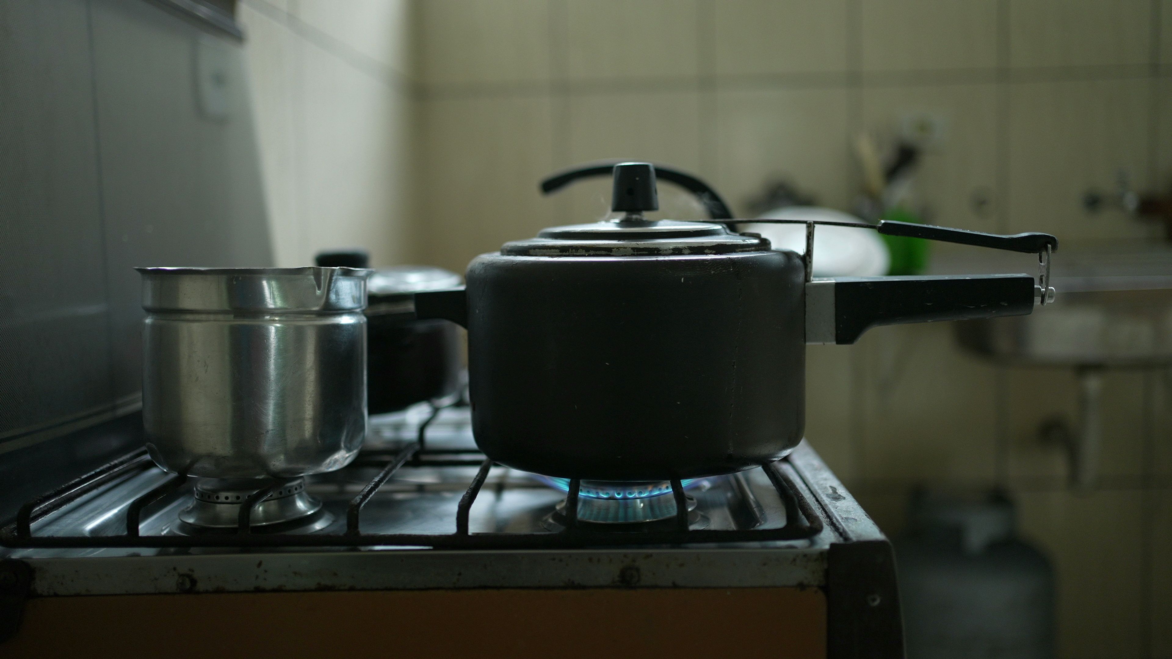 A pressure cooker and other pots on a natural gas stove.