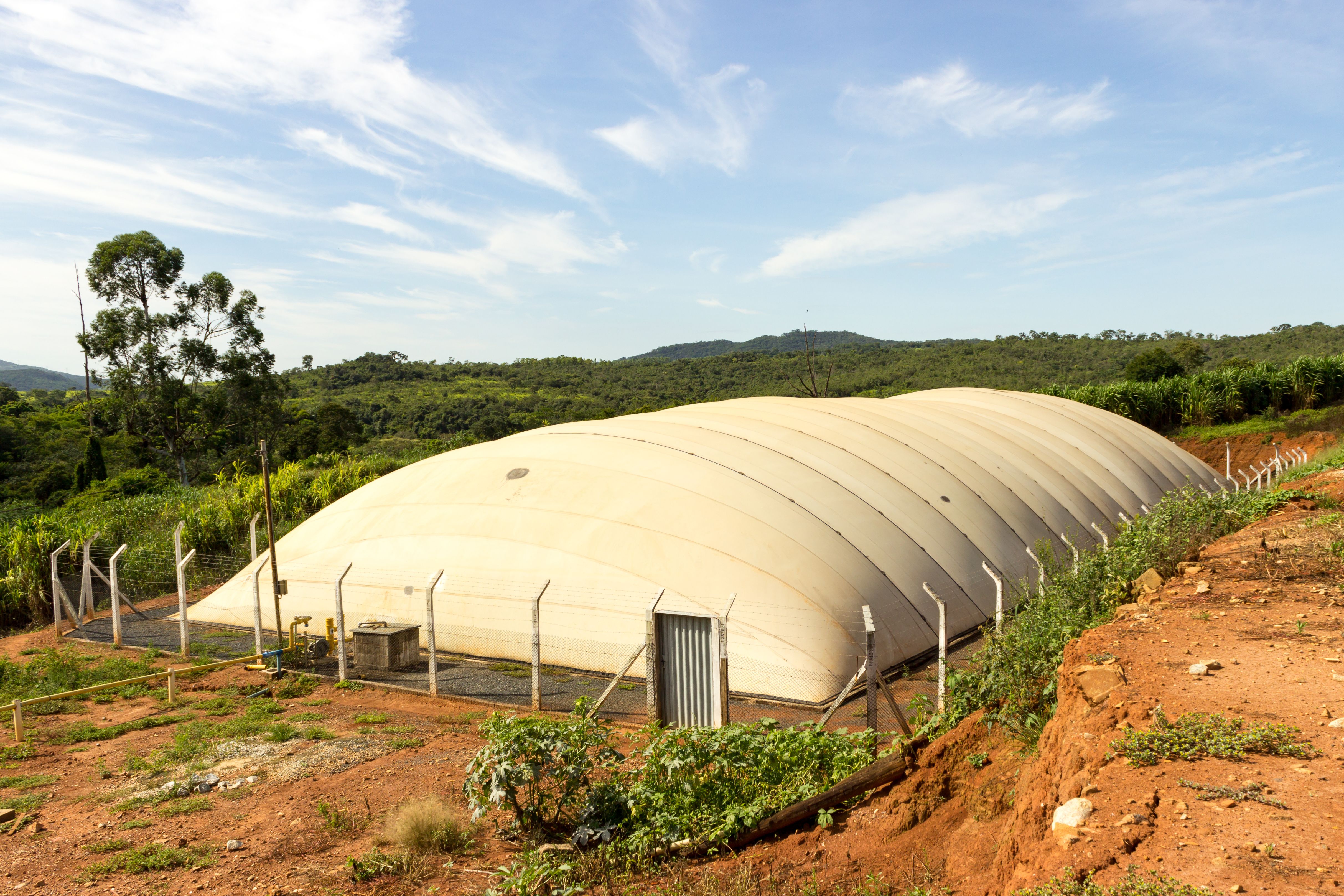 A large white biodigester on an open field. 