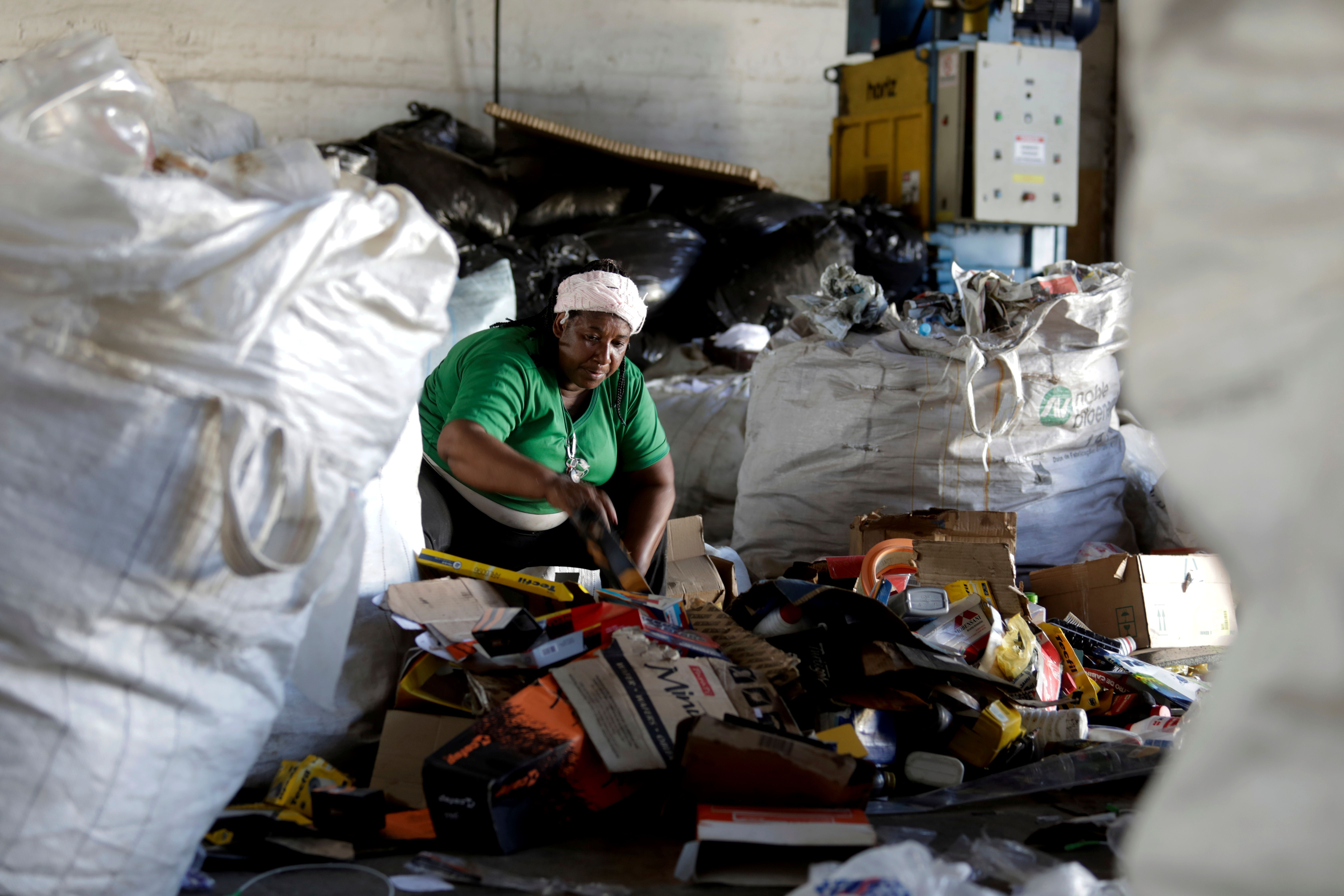 A worker at a recycling cooperative sorting through a pile of waste in Brazil.